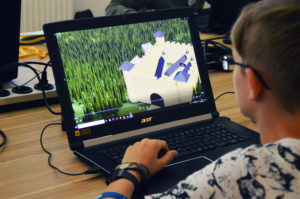 Zu sehen ist ein aufgeklappter Laptop, mit dem ein Junge an einem 3D-Modell arbeitet.